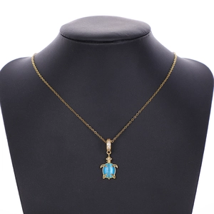 Close-up of golden turtle pendant with blue cat eye stone on a black jewelry bust