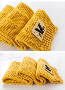 Detailed macro view of yellow chunky knit scarf with stitched leather V letter patch