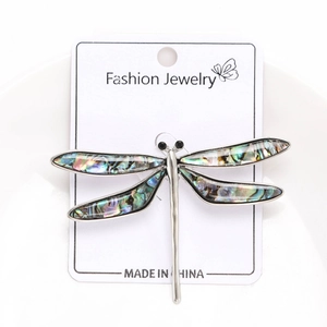 Close-up of vintage dragonfly brooch with iridescent abalone shell wings on silver base