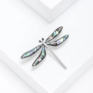 Macro detail of vintage dragonfly brooch with emerald shell wings on silver metal base