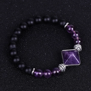 Close-up of matte black onyx beads with a purple amethyst pyramid and silver spacer charms