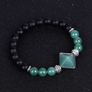 Detail view of matte black agate beads and green pyramid crystal on a stretch bracelet