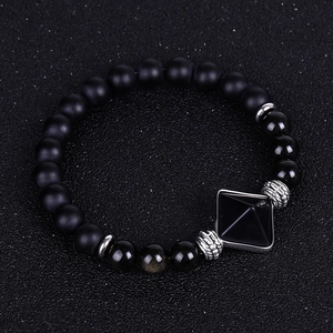 Close-up of matte black onyx beads with a silver-framed pyramid pendant on the bracelet