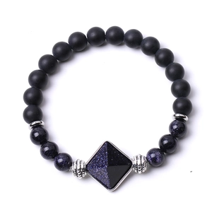 Detailed macro of matte black onyx beads and pyramid blue stone pendant on bracelet