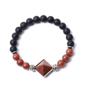 Detailed macro view of matte black agate beads and goldstone pyramid on the beaded bracelet