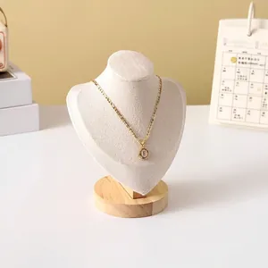 Detail of a gold letter E pendant necklace on a wooden portrait jewelry display stand