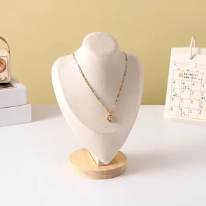 Detail of golden necklace with letter E pendant on white bust display with wood base