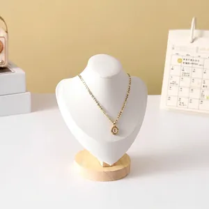 Detail of a gold Figaro chain necklace with a letter E coin pendant on a white neck bust