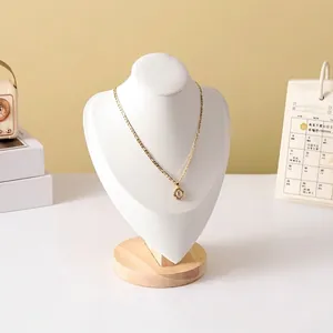 Detail of gold Figaro chain with round letter E pendant on a white wooden neck display