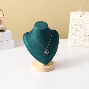 Detailed view of silver heart pendant with blue gems on a green velvet necklace stand