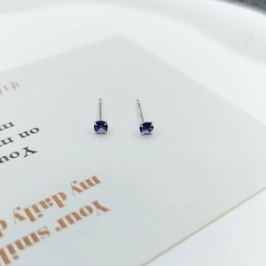 Detail view of S925 silver stud earrings with purple cubic zirconia in a four-prong setting