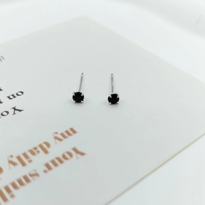 Macro shot of S925 sterling silver ear studs with black round zircon in 4-claw setting