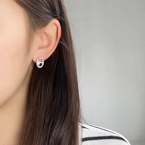 Close-up of polished silver anchor link stud earrings worn on a model's earlobe