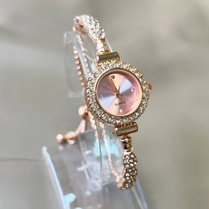 Detail of rose gold ladies quartz watch featuring rhinestone bezel and pink sunray dial