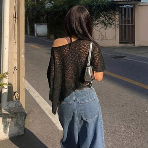 Detail view of a black lace off-shoulder top with intricate floral pattern and sheer mesh