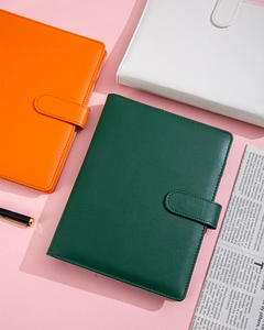 Detailed view of A5 leather budget binders in orange, white, and dark green with pen