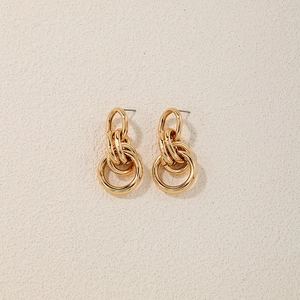 Detail of interlocking golden multi-layered metal ring earrings with polished finish