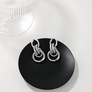 Polished silver multi-layer interlocking metal hoop earrings on black display tray