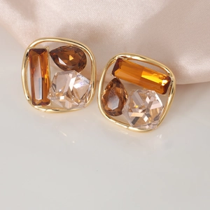 Elegant gold geometric earrings with amber and champagne crystals on silk background