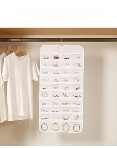 Close-up of hanging jewelry organizer with transparent PVC slots and four golden metal hooks