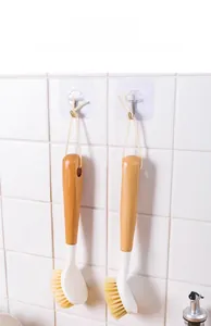 Long handle kitchen brush with wooden grip and hanging rope on a white tiled wall