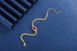 Macro shot of gold Cuban chain bracelet with rectangular red ruby and pavé crystals