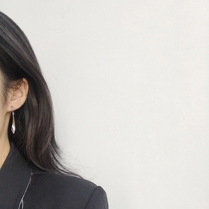 Detail of S925 sterling silver asymmetrical wave earrings worn with a black blazer