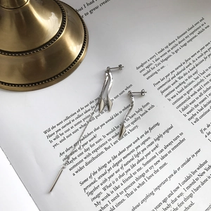 Macro detail of asymmetric S925 sterling silver long chain and curved stud earrings