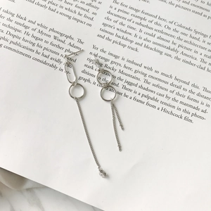 Detailed macro of asymmetrical S925 silver hoop earrings with long chain tassels