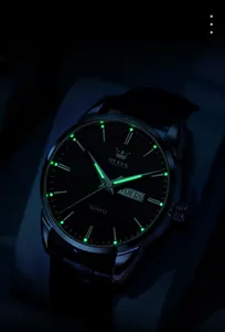 Gros plan des aiguilles lumineuses et double calendrier sur montre à quartz OLEVS