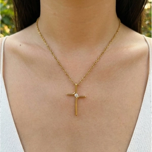 Close-up detail of a minimalist gold cross necklace with a sparkling AAA zircon