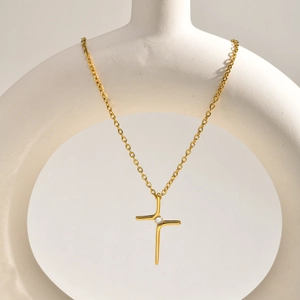 Minimalist gold cross necklace featuring AAA zircon pendant displayed on white ceramic