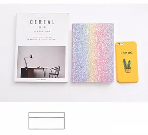 Size comparison of rainbow laser notebook next to an A4 magazine and smartphone