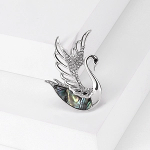 Detailed close-up of a silver swan brooch with crystals and iridescent abalone shell inlay