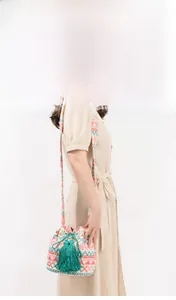 Detail of bohemian bucket bag with geometric patterns and large green tassels