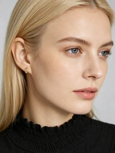 Close-up of golden infinity stud earrings with sparkling pave zircon on female model