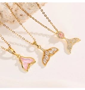 Macro shot of three gold mermaid tail necklaces with pink gems and pavé zircons