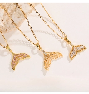 Detailed macro shot of three gold fishtail pendants with zircon and pearl accents