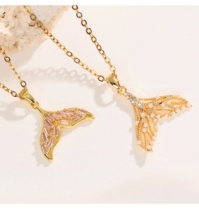 Detail view of two mermaid tail pendant necklaces with pink gems and gold filigree