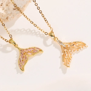 Golden mermaid tail necklace with pink zircon and pearl charms on stone display