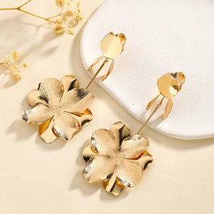 Macro shot of gold floral tassel earrings with layered petals and brushed metal texture