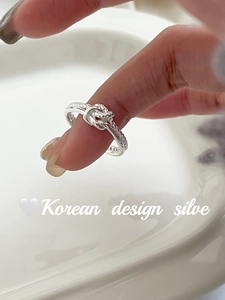 Detail of S925 sterling silver twist knot ring with elegant woven texture on white tray