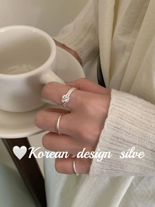 Detailed view of three minimalist S925 silver twist knot rings on model holding a cup