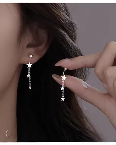 Macro detail of S925 silver star tassel earrings worn on ear with dangling chain