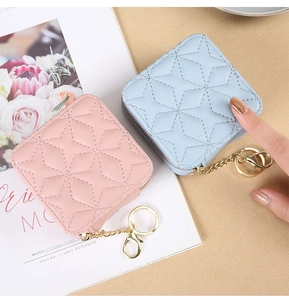Mini quilted lipstick cases with gold keychains in pink and blue shown in palm