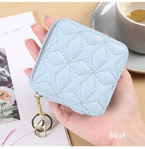 Close-up of light blue quilted mini makeup bag with star stitching and a gold keychain
