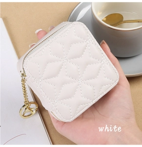 Close-up of white quilted mini lipstick case with gold zipper star charm held in hand