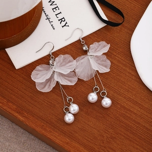 Elegant detail shot showing white frosted flower petal earrings with pearl tassels