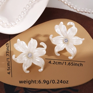 Detailed view of white petal stud earrings with a central clear rhinestone