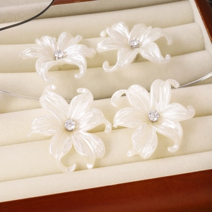 Detail view of elegant white pearl-luster petal earrings with crystal centers in box